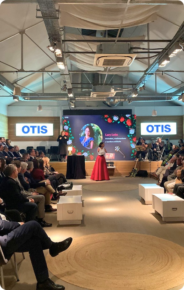 Una mujer con discapacidad física exponiendo ante un público en la entrega de premios de OTIS 