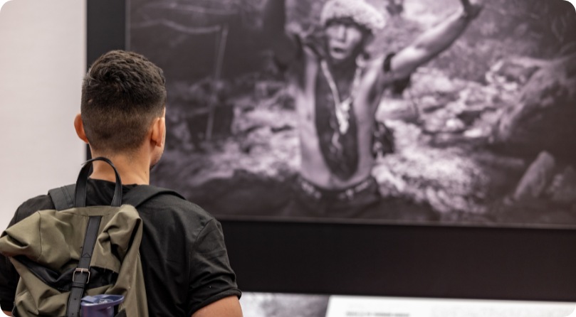 Un hombre observando atentamente una fotografía en blanco y negro colgada en la pared.